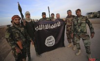 Iraqi Shi'ite fighters pose with an Islamic State flag which they pulled down on the front line in Jalawla