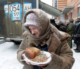 An elderly woman holds a plate of food she received at a distribution point for homeless in Moscow
