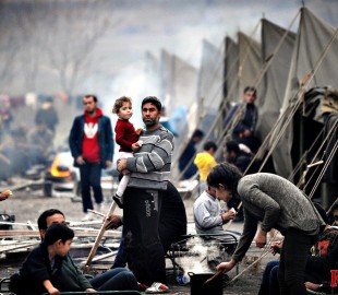 A Syrian refugee holds a baby in a refug...A Syrian refugee hold