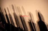 Shadows of members of a panel are seen on a wall before a meeting about the 